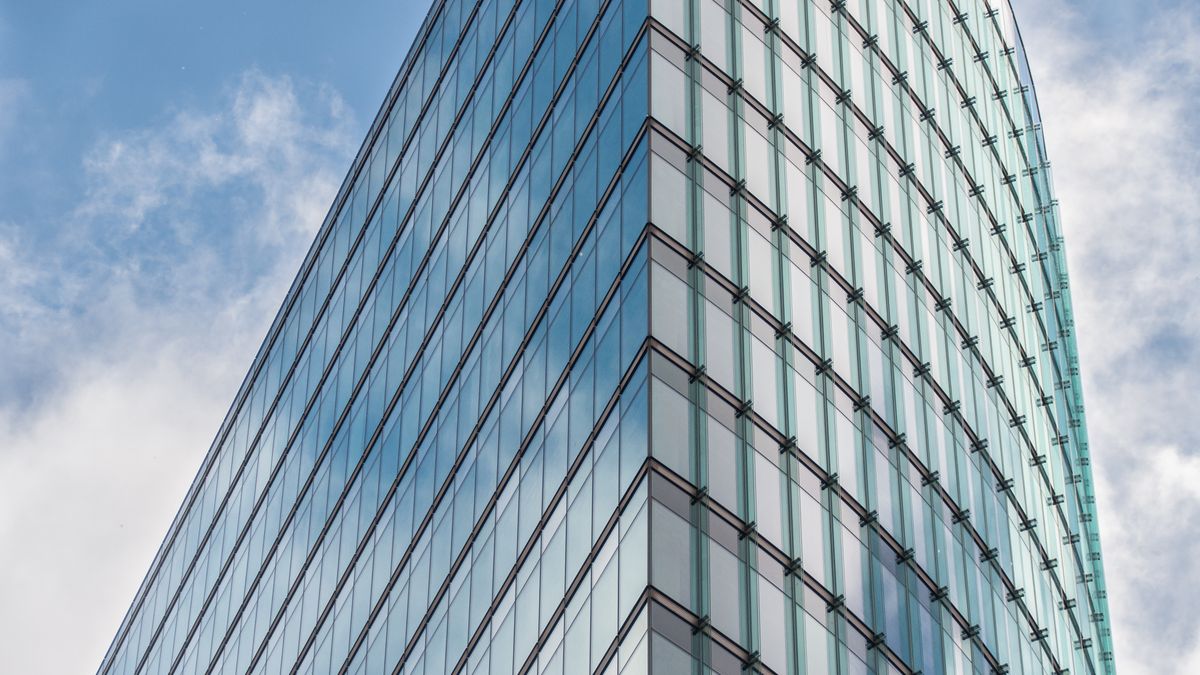 A modern corporate glass skyscraper against a blue sky